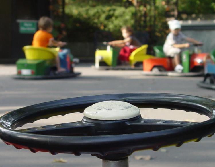 Blick über den Lenker eines Minicars auf spielende Kinder